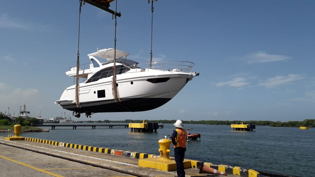 A yacht suspended in a travel lift on the hard at a boatyard