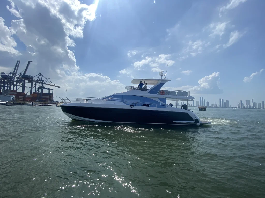 Flybridge motor yacht cruising past a cargo port